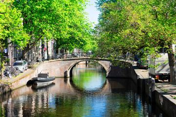Fototapeta na wymiar bridge of Amsterdam over canal ring landmark in old european citye, Holland Netherlands. Amsterdam spring scenery with tree lush.