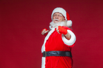 Christmas. Santa Claus with red bandages wound on his hands for boxing imitates kicks. Kickboxing, karate, boxing. Isolated on red background.
