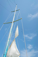 Fototapeta premium White sail of a sailing boat against sky. Sails of river sailing yacht in the wind against the blue sky