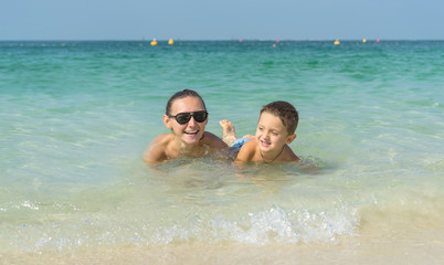 Obraz premium Happy smiling family having fun on tropical white beach (Maldives islands). Mother and cute son. Positive human emotions, feelings, joy. Spring, summer and winter holidays.