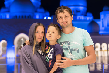 Mother with cute son and father dreaming at the grand mosque of Sheikh Zayed Mosque in Abu Dhabi wearing abaya, paranja in night time. Travelling. Concept for advertising poster Dubai, Abu Dhabi.
