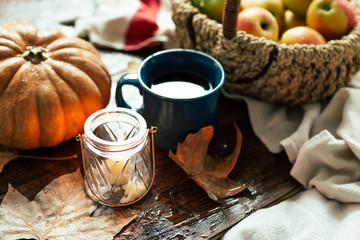 Autumn, a mug of tea and raindrops, fallen leaves, coziness, apples in a basket and pumpkin