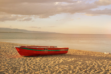 Fishing boat on the sandy beach, the sea at sunset.