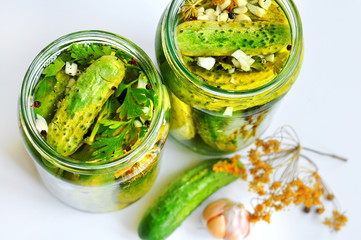 Jars of pickled vegetables: organic small cucumbers with herbs and spices green parsley garlic dill. Marinated and canned food.
