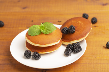Delicious pancakes with BlackBerry and mint, on a white plate and a wooden table