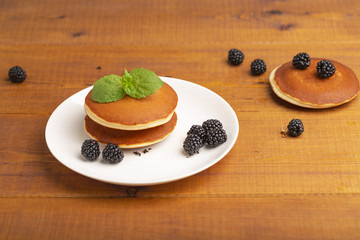 Delicious pancakes with BlackBerry and mint, on a white plate and a wooden table