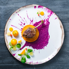 Duck leg confit with cabbage puree and persimon on white plate, restsurant meal