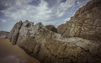 Fototapeta na wymiar Travel, Beach with rocks in summer. Playa de la Arnía in Santander, Spain