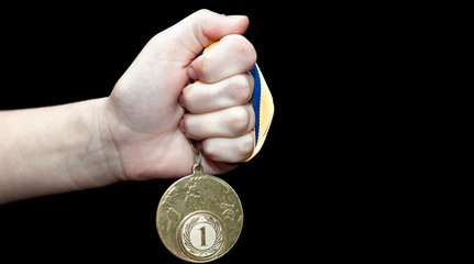Plakat Woman hand holding gold medal against black background. Award and victory concept