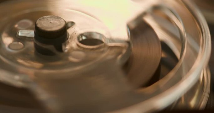 A macro shot of a tape reel spinning on a vintage audio recorder.