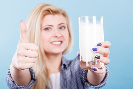 Woman holding glass of milk showing thumb up