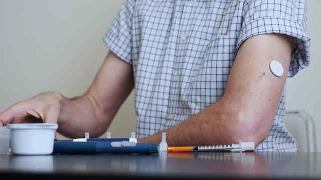 A man brings to the hand the reading device to the sensor for measuring glucose
