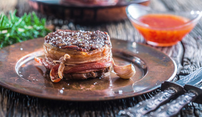 Portion of juicy beef tenderloin steak covered bacon.