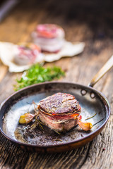 Portion of juicy beef tenderloin steak covered bacon.