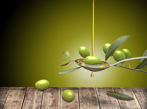 Olive oil jet over a olive branch in a spoon