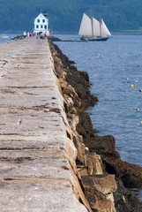 Breakwater Leads to Lighthouse as Schooner Sailing Vessel Passes By