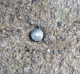 Polish coat of arms on the button. Silver eagle on the background of concrete. Grunge texture old photo