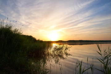 Bright Sunny landscape of the dawn sun and the lake. Bright reflections of sky and clouds