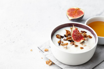Healthy breakfast concept. Homemade yoghurt with organic granola, nuts and fig fruits in small bowl.