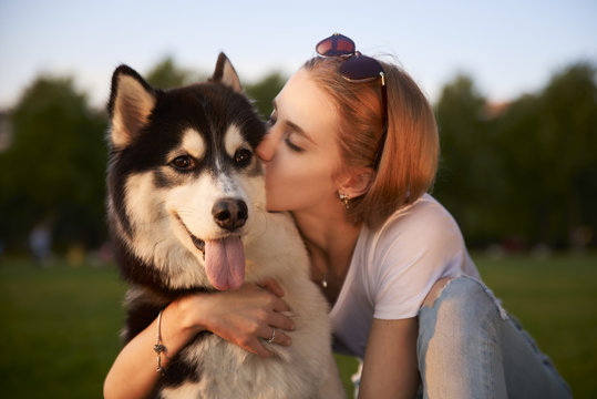 A young girl while walking in the Park with a dog hugs the dog Laika and kisses. Casual clothes, jeans and a white t-shirt