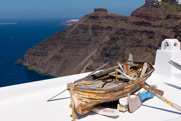 Old wooden broken boat on roof of house, located at Santorini island, Greece