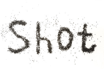Steel shot for blasting machine. Inscription SHOT on a white surface with scattered small metal granules.