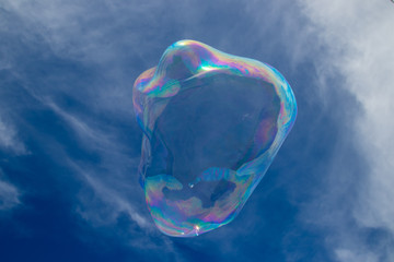 Giant colourful bubble with light clouds and blue sky, no people, family fun, summer.