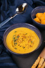 Pumpkin soup in blue bowl topped with fresh herb