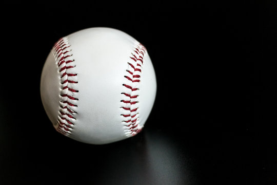 white baseball with red seams leather ball on black background