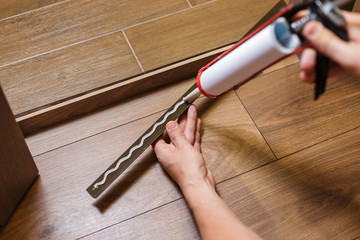 Home Door Installation. Worker use a metal profile to close the corner seam on the floor. Man...