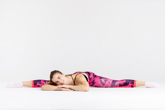 Young sportwoman stretching muscles on white background