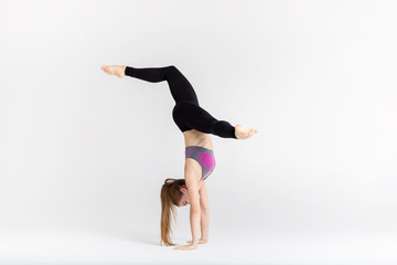 Young sportwoman stretching muscles on white background