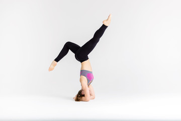 Young sportwoman stretching muscles on white background