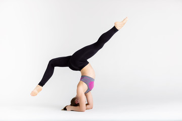 Young sportwoman stretching muscles on white background