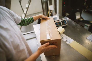 Closeup of female hands closing box in factory.