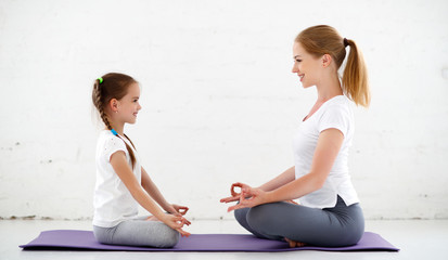 mother with child practicing yoga in lotus pose .