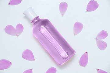Glass bottle with perfume and flower petals. White background.