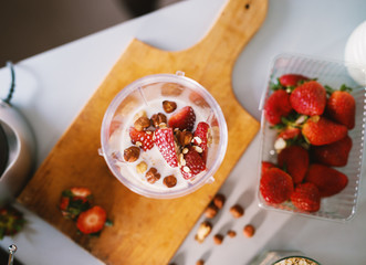 View of contents within blender bowl being fresh fruit milk and cereals that are standing on top of the wooden cutting board.