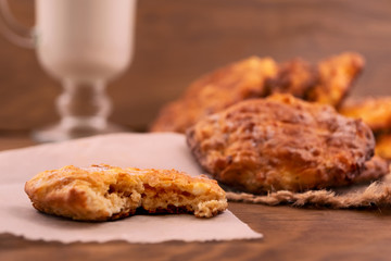 Homemade round cookie, broken and stacked on paper, wooden background.