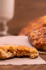 Broken cookies with cottage cheese filling on paper, wooden background, vertical frame.