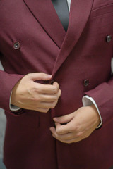 Novio ajustando su traje de color marsala