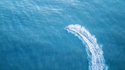 Scooter at the sea surface. Aerial view of luxury floating boat on transparent turquoise water at sunny day. Summer seascape from air. Top view from drone. Seascape with motorboat in bay. 