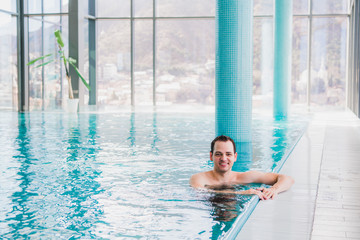 Shot of a handsome young happy man in the indoor swimming pool