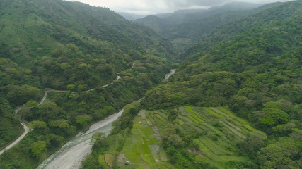 Obraz premium Aerial view of mountain valley in the cordillera, river, rice terraces, farmland in the Philippines, Luzon. Aerial view of mountains covered forest, tree. Cordillera region.