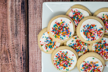 Delicious vanilla circle shaped frosted sugar cookies with colorful rainbow sprinkles. Plated view...