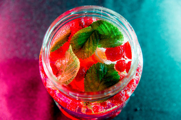 Summer drink coctail in glass jar, berries and mint on wooden table