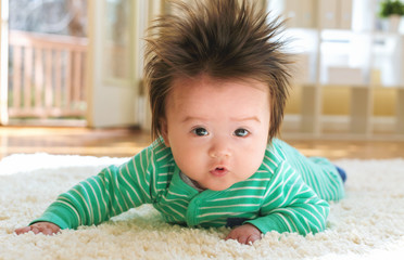 Happy newborn baby boy playing on the carpet