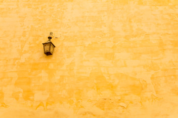 An antique lamp hanging on the yellow wall in Meknes city, Morocco.