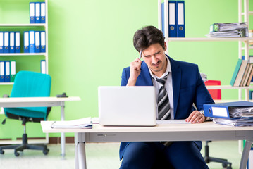 Businessman unhappy with excessive work sitting in the office 