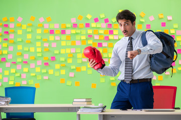 Man with boxing gloves in the office with many conflicting prior